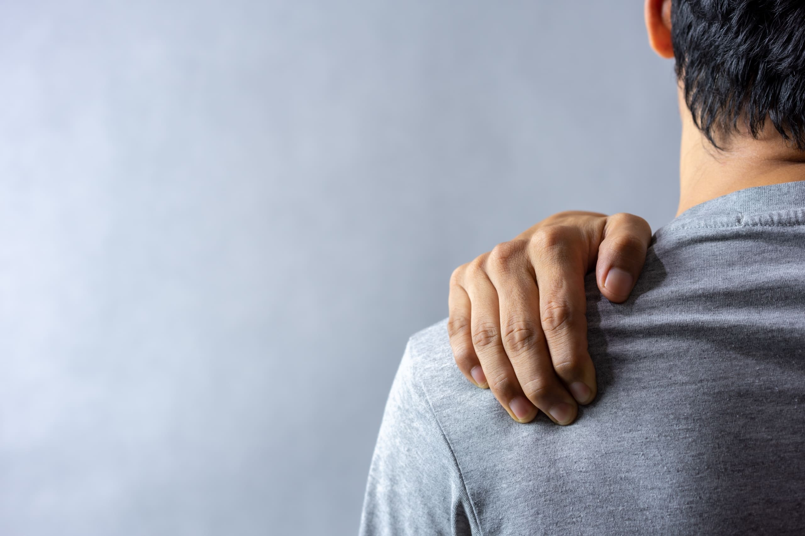 Close up of a man gripping his shoulder