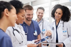 Group of medical professionals smiling and looking at a tablet